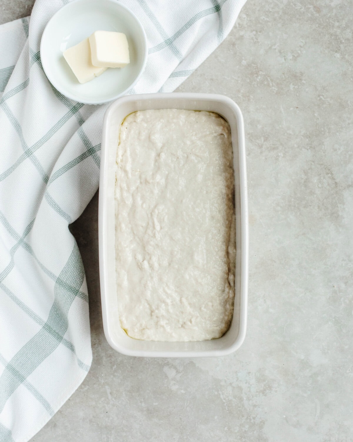 Beer bread batter spread evenly into a white loaf pan.