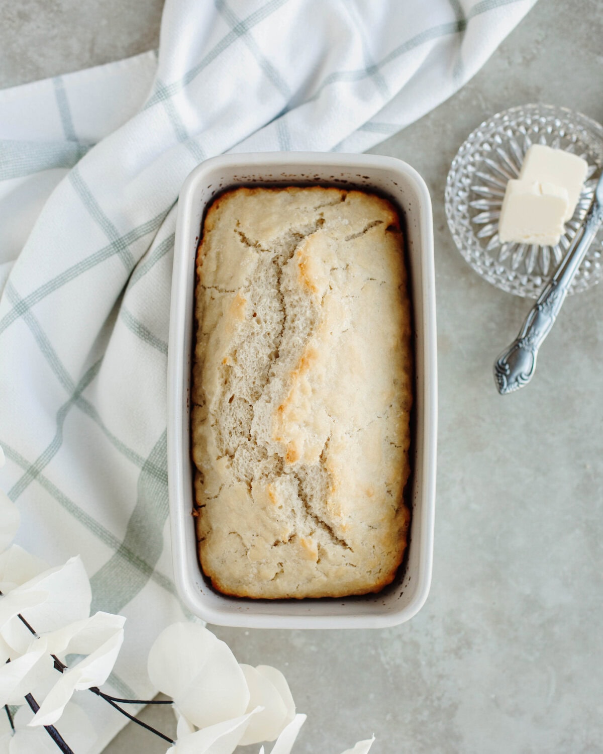 A baked loaf of beer bread in a white loaf pan.