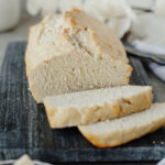 A sliced loaf of beer bread ready to serve from a wood cutting board.