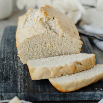 A sliced loaf of beer bread ready to serve from a wood cutting board.