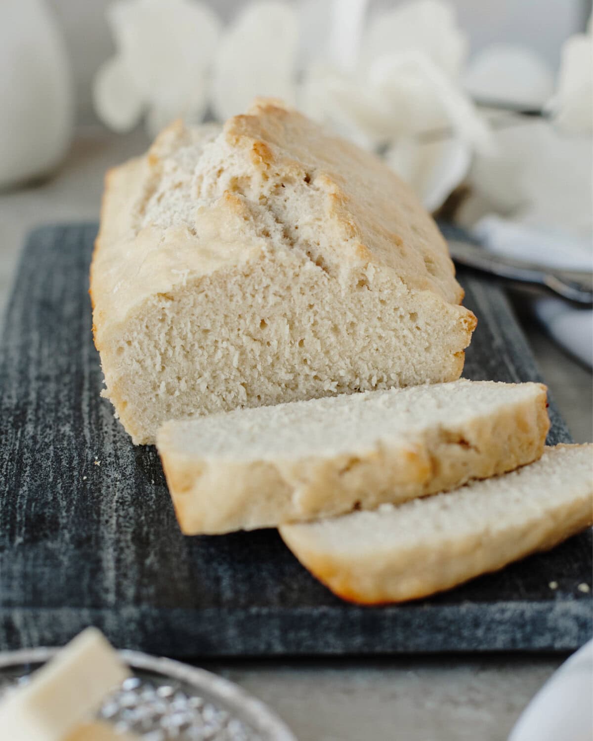 A sliced loaf of beer bread ready to serve from a wood cutting board.