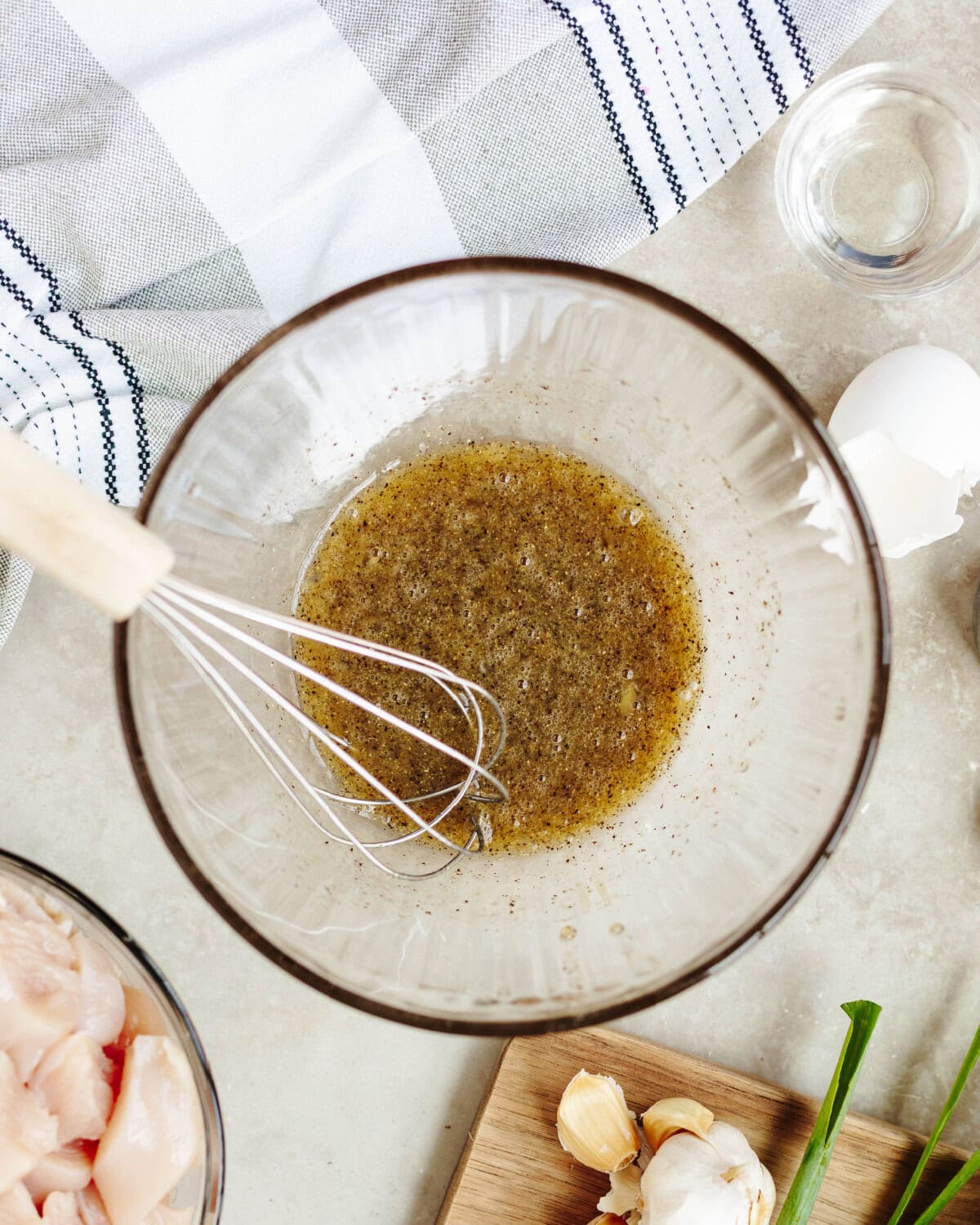 Egg, salt, pepper, and oil whisked together in a small glass bowl.