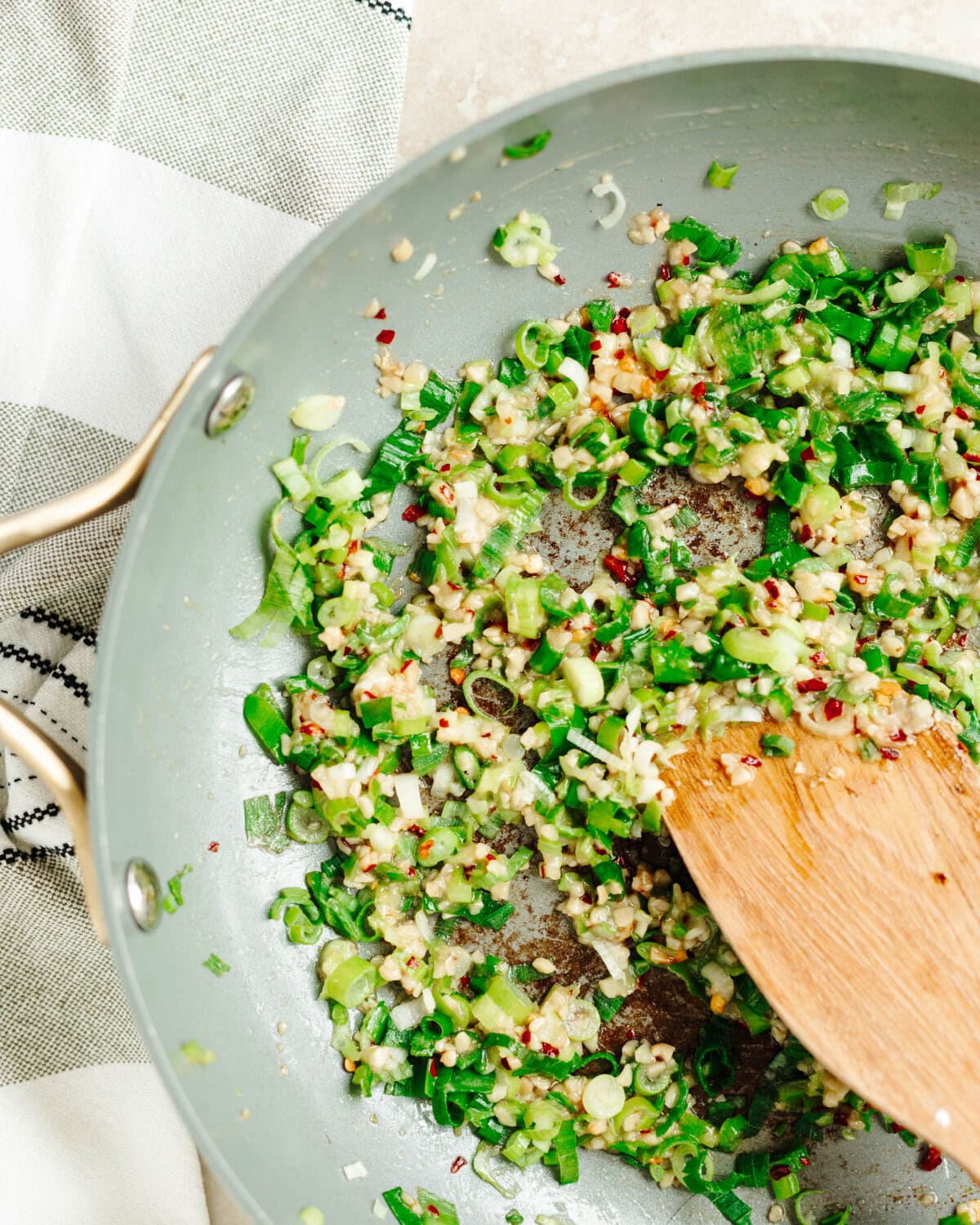 Crushed red pepper and green onions cooking in a skillet.