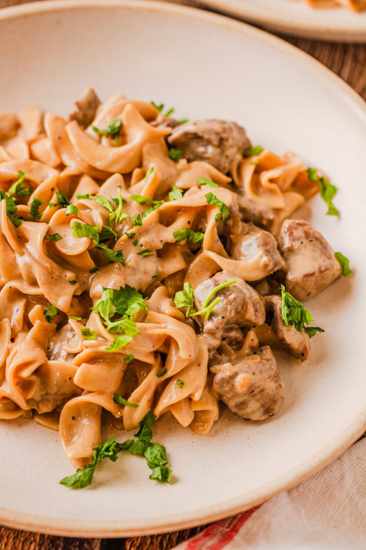 French onion beef and noodles served on a white dinner plate.