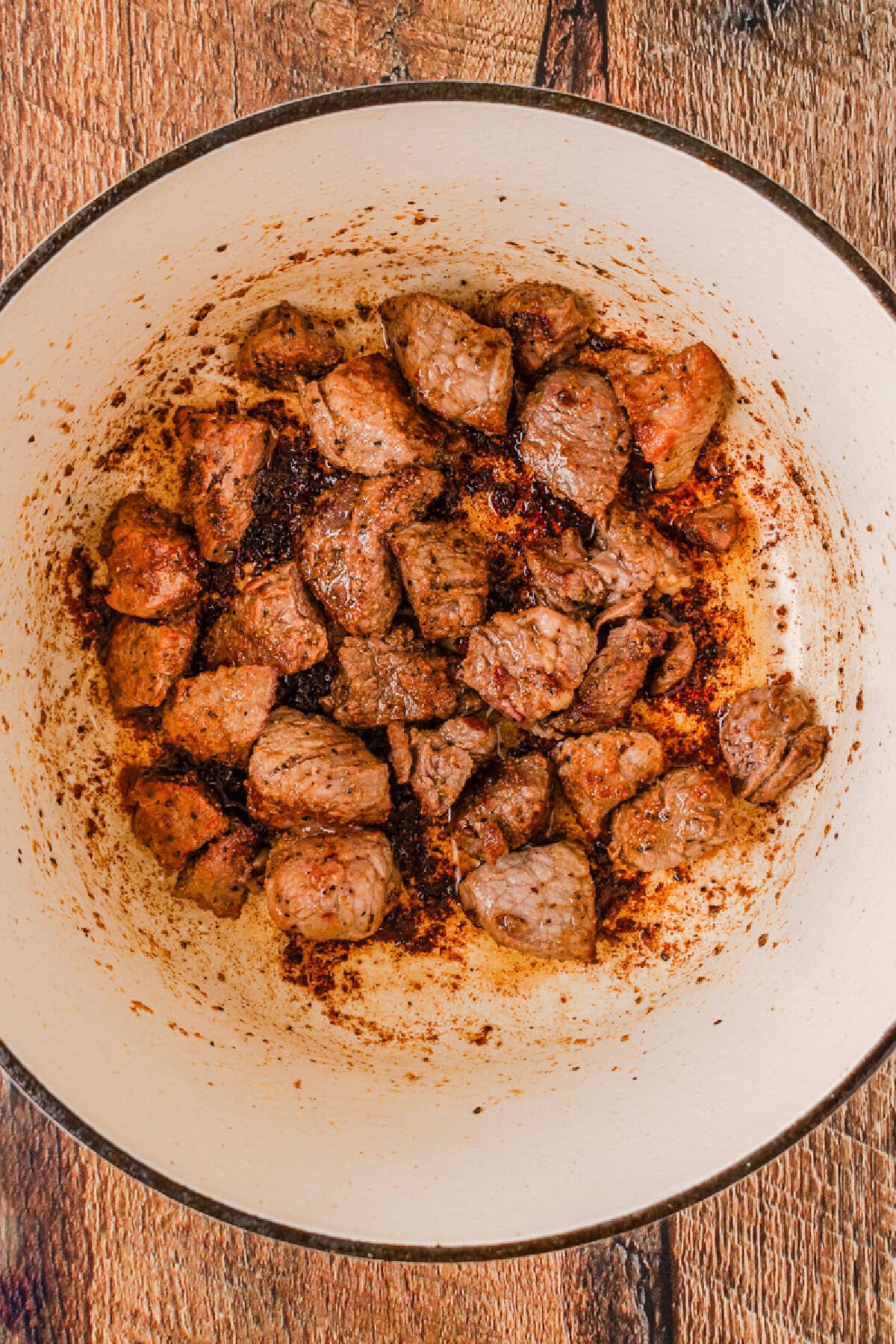 Stew meat cooking until browned in a Dutch oven.