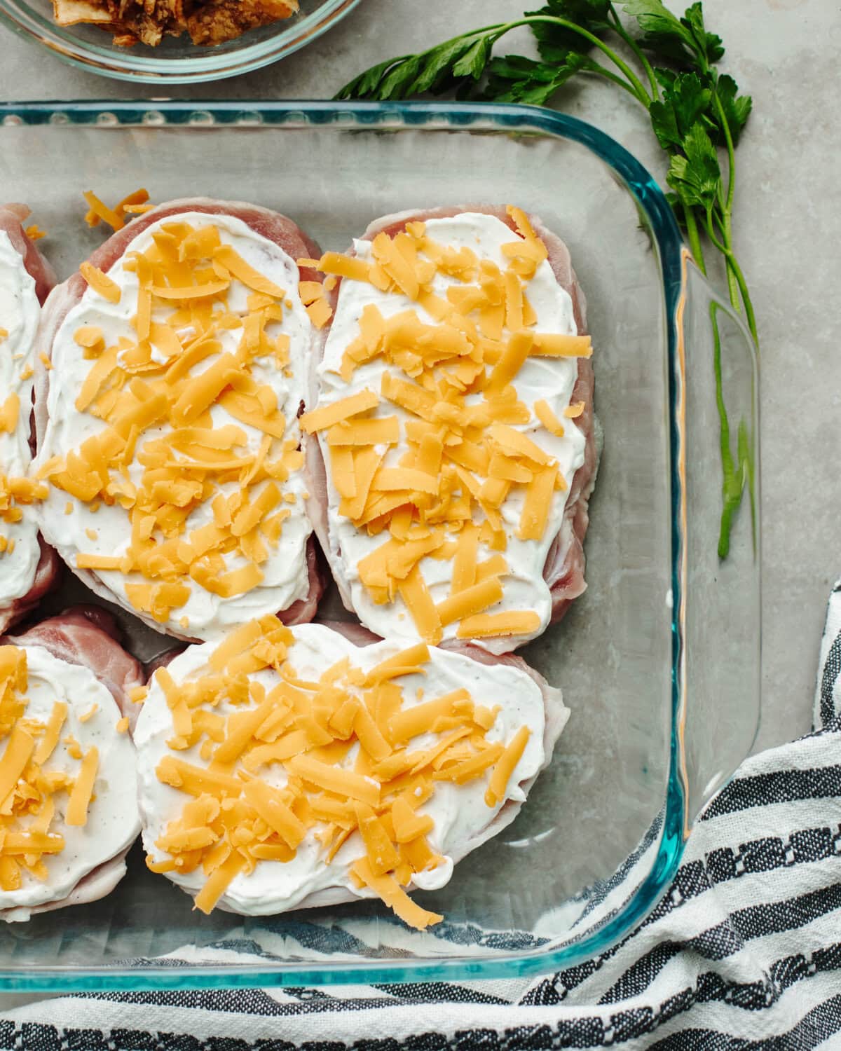 Shredded cheddar cheese sprinkled on top of smothered boneless pork chops.