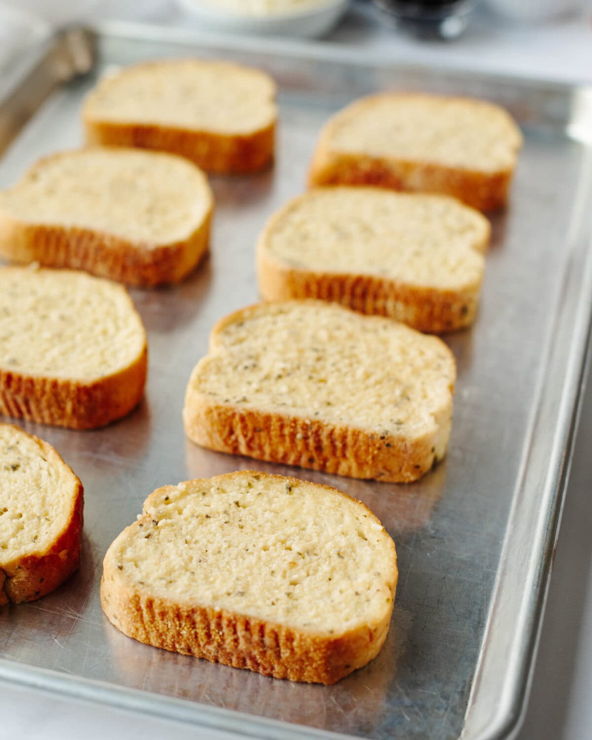 Garlic toast placed in a single layer on a baking pan.