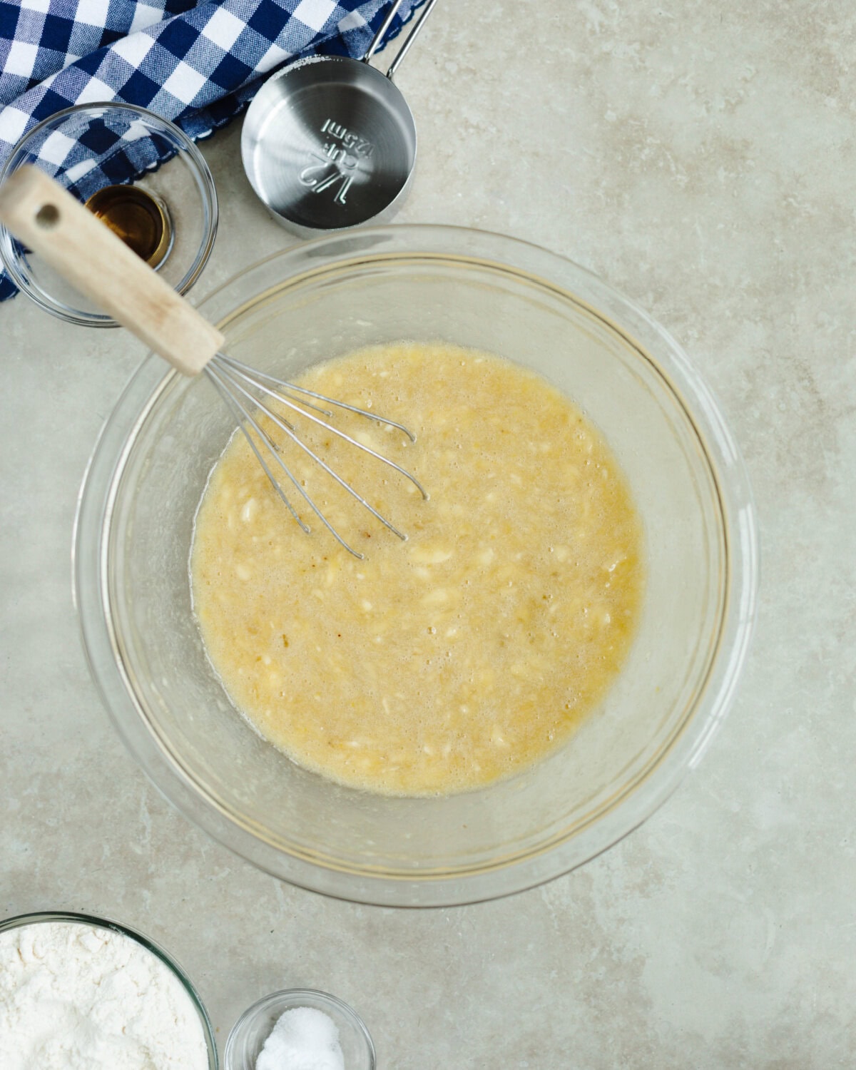 Melted butter, egg, sugar, and vanilla combined with mashed banana in a glass mixing bowl.