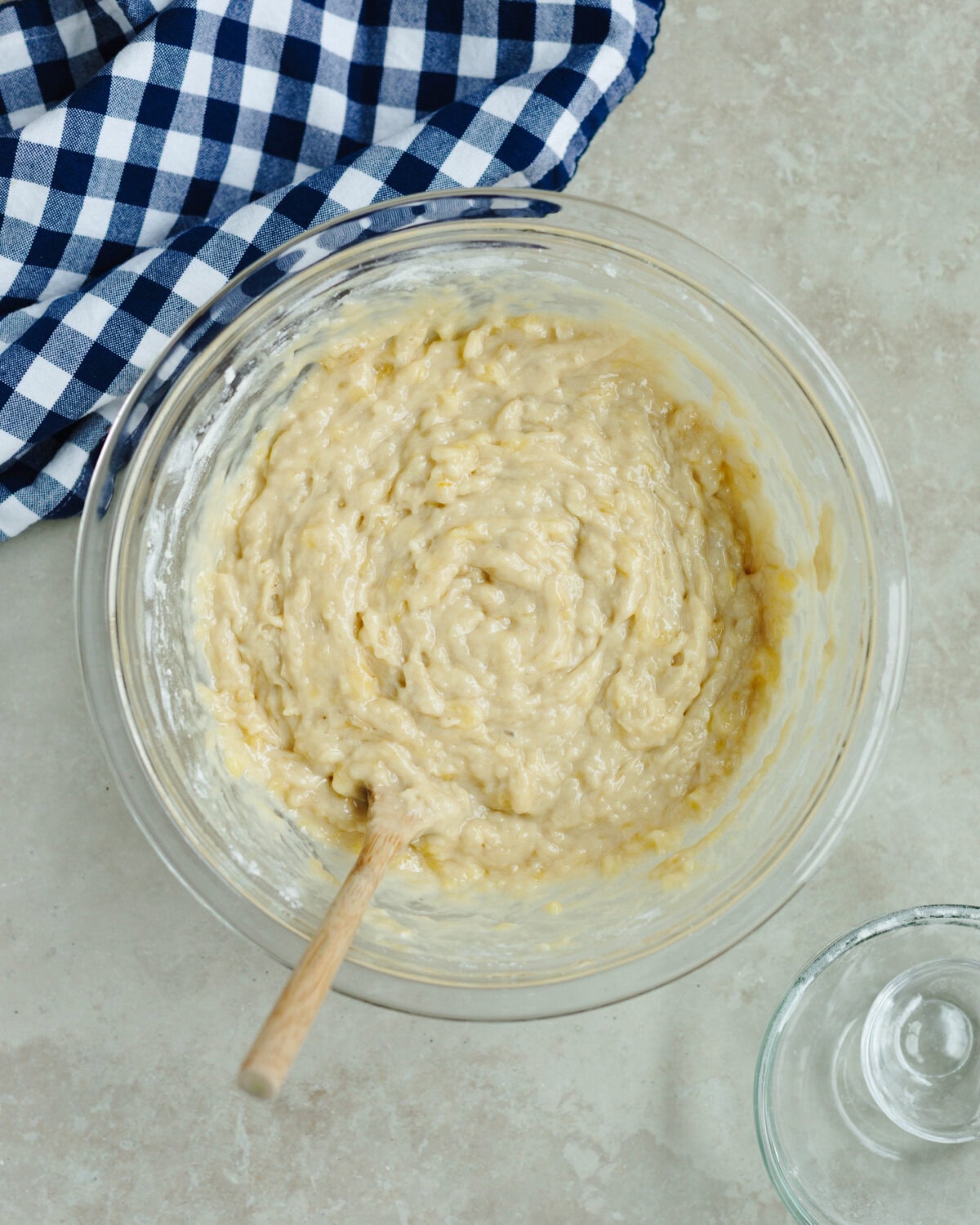 Baking soda, salt, and flour folded into a wet banana mixture in a bowl.
