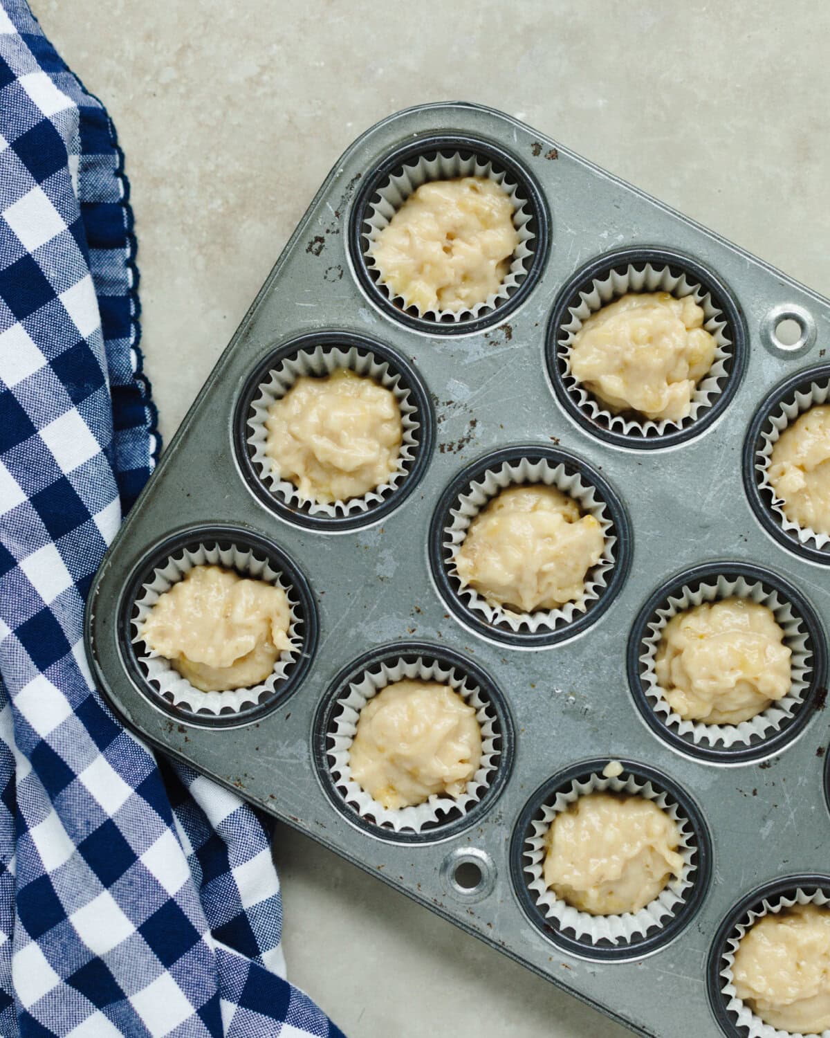 Muffin batter placed into white paper liners in a mini muffin pan.