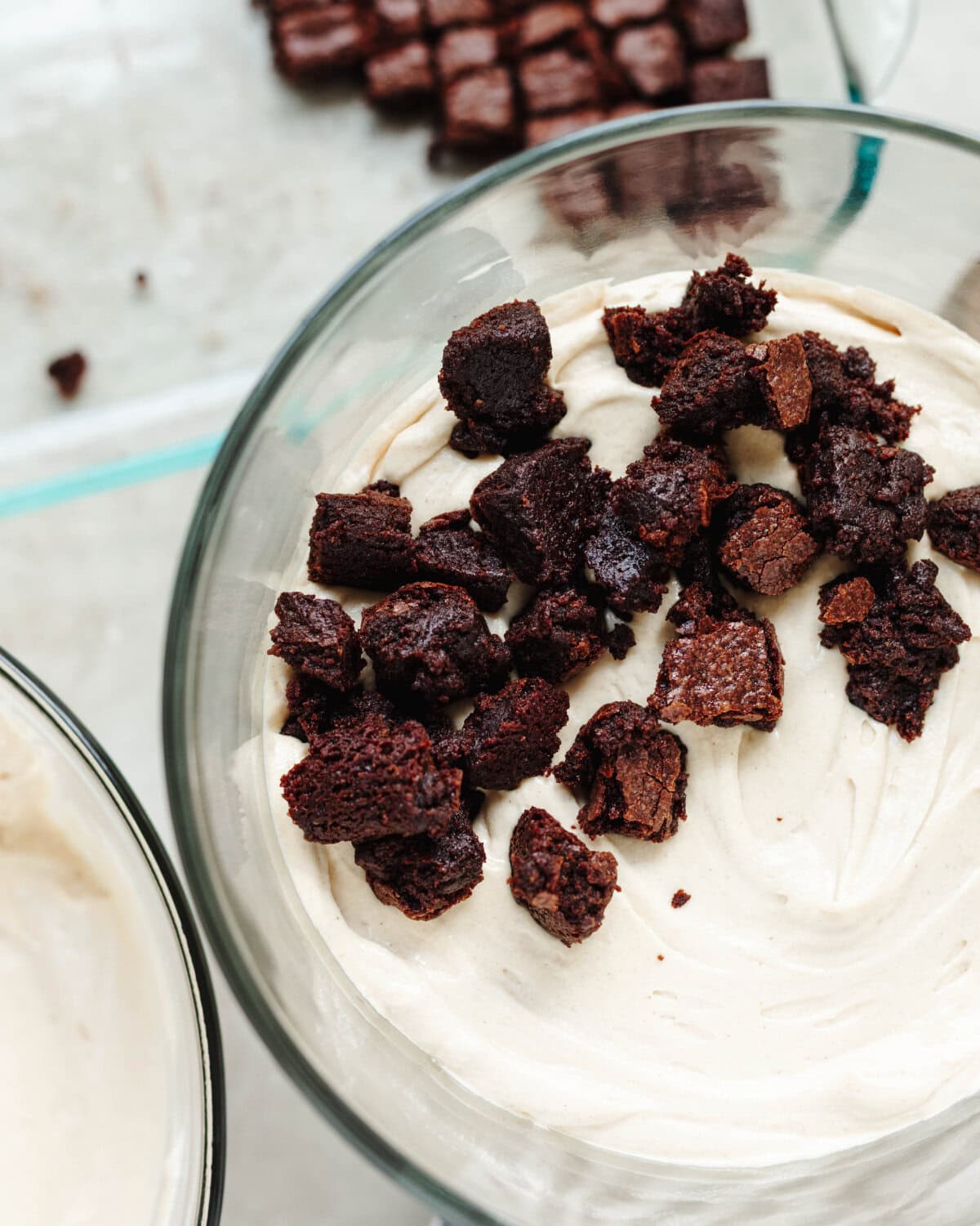 Chopped brownie pieces arranged in a single layer on top of a cream cheese peanut butter mixture.