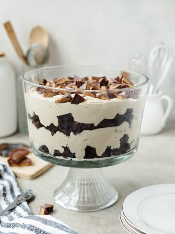 A side view of a peanut butter brownie trifle ready to serve from a glass trifle bowl.