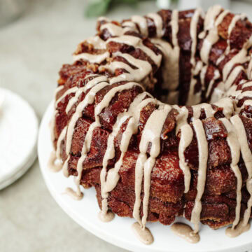 Icing drizzled on top of pumpkin spice monkey bread served on a cake stand.