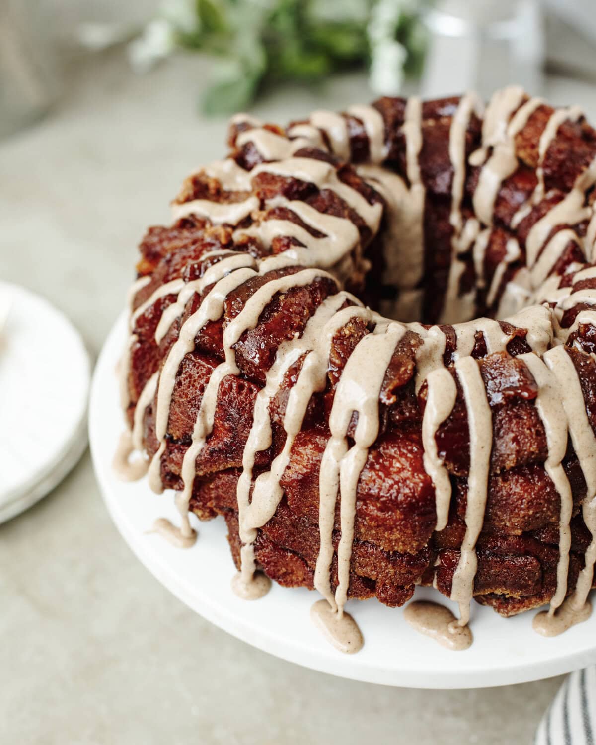 Icing drizzled on top of pumpkin spice monkey bread served on a cake stand.