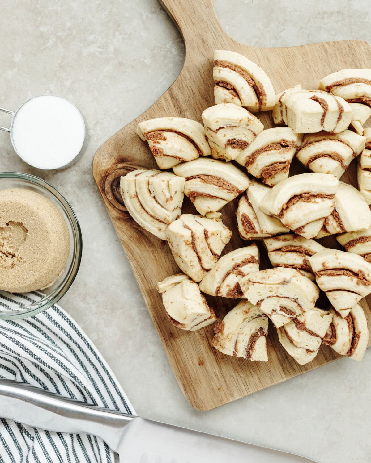 Sliced cinnamon roll pieces on a wood cutting board.