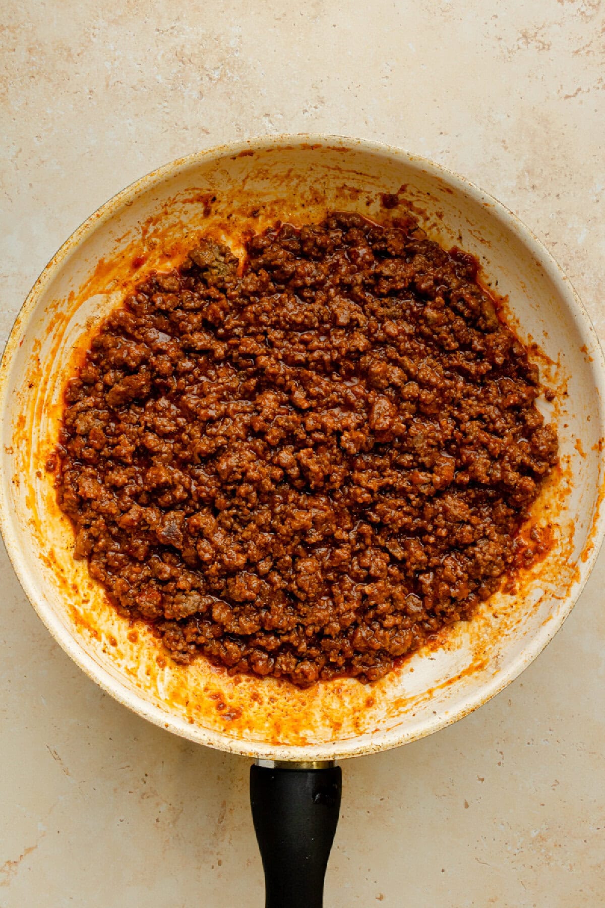 Ketchup, water, brown sugar, Worcestershire sauce, mustard, garlic powder, onion powder, and salt added to cooked ground beef in a skillet.