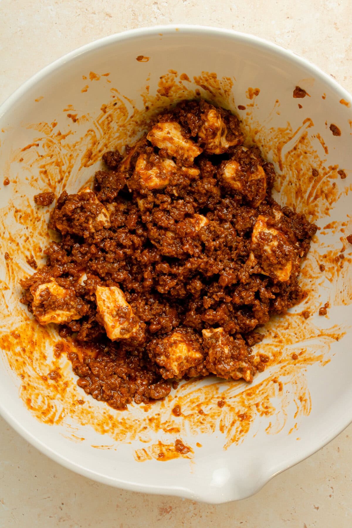 Biscuit pieces and a ground beef mixture combined in a mixing bowl.