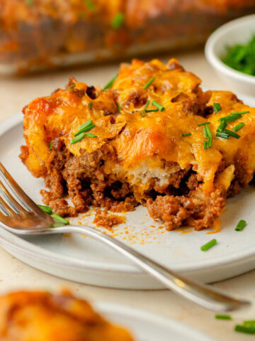 An up close look at a piece of sloppy joe biscuit casserole served on a white plate.