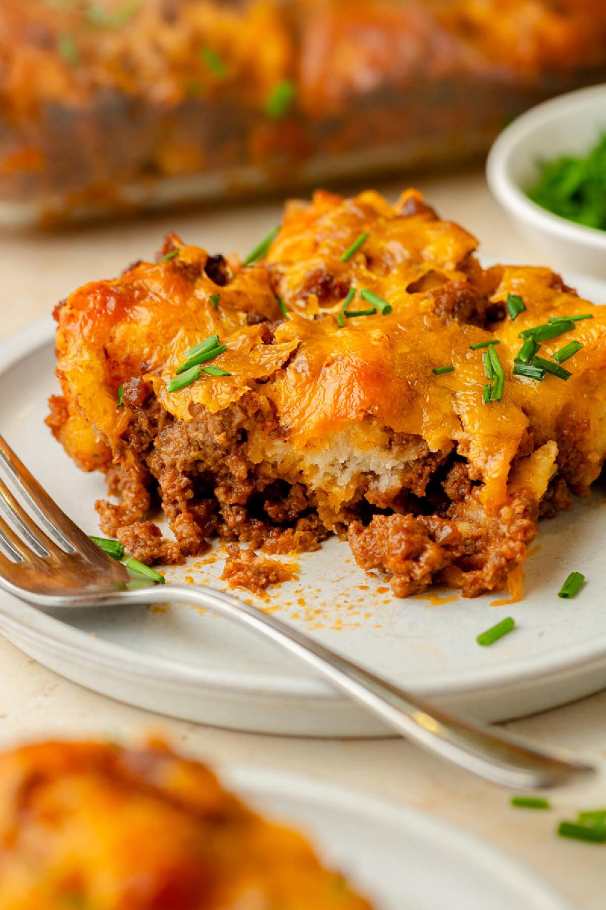 An up close look at a piece of sloppy joe biscuit casserole served on a white plate.