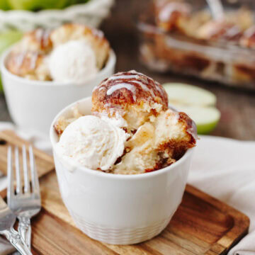 A white bowl with a scoop of apple cinnamon cream cheese bake and vanilla ice cream ready to enjoy.