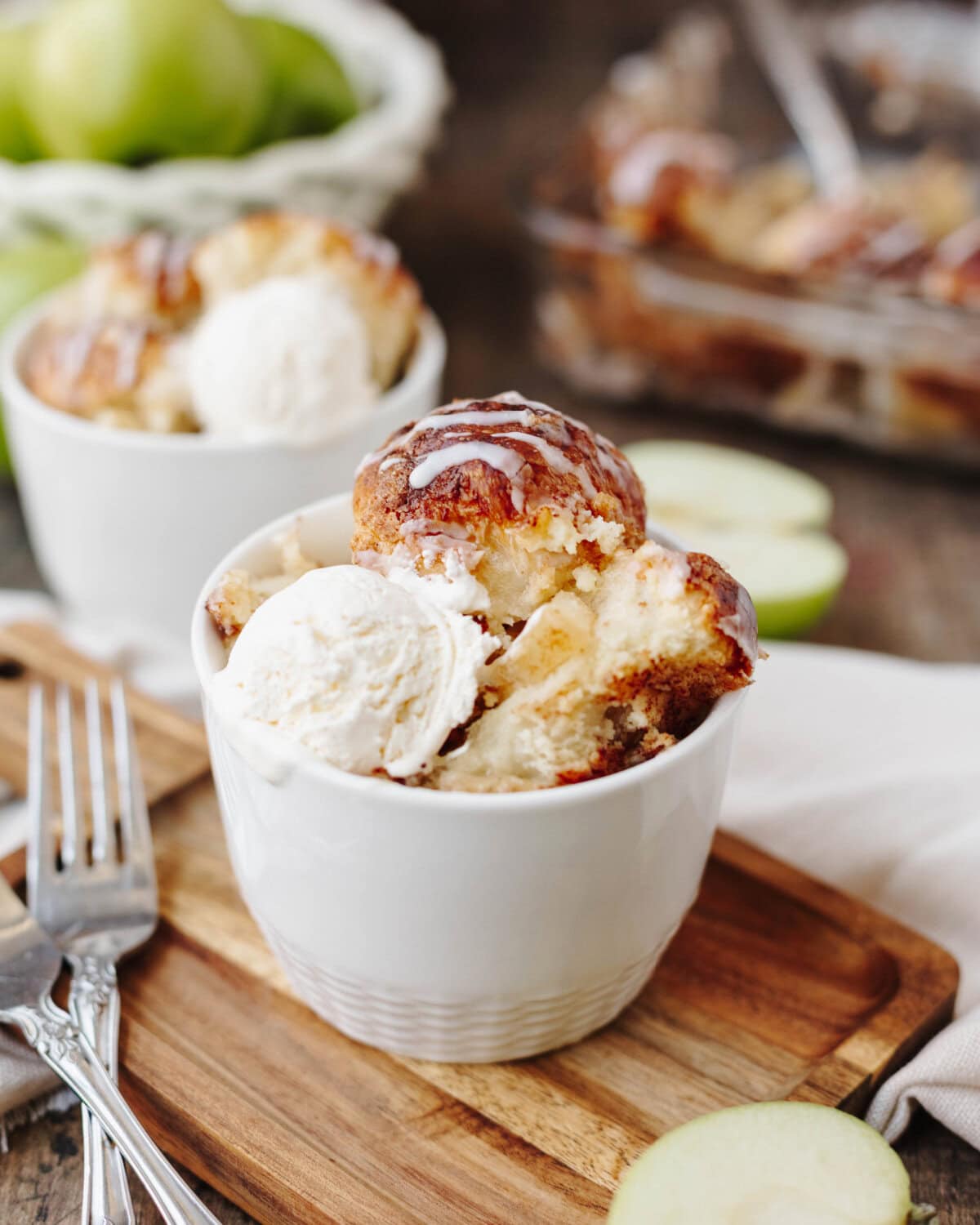 A white bowl with a scoop of apple cinnamon cream cheese bake and vanilla ice cream ready to enjoy.