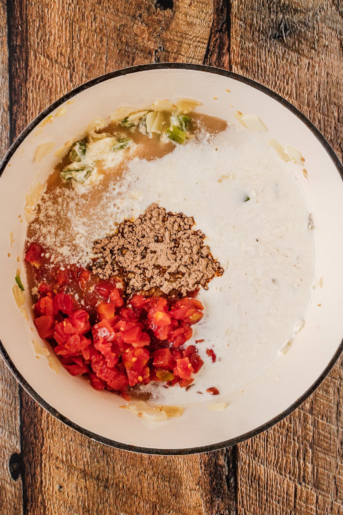 Diced tomatoes, fajita seasoning, cream, broth, peppers, and onions added to a Dutch oven.