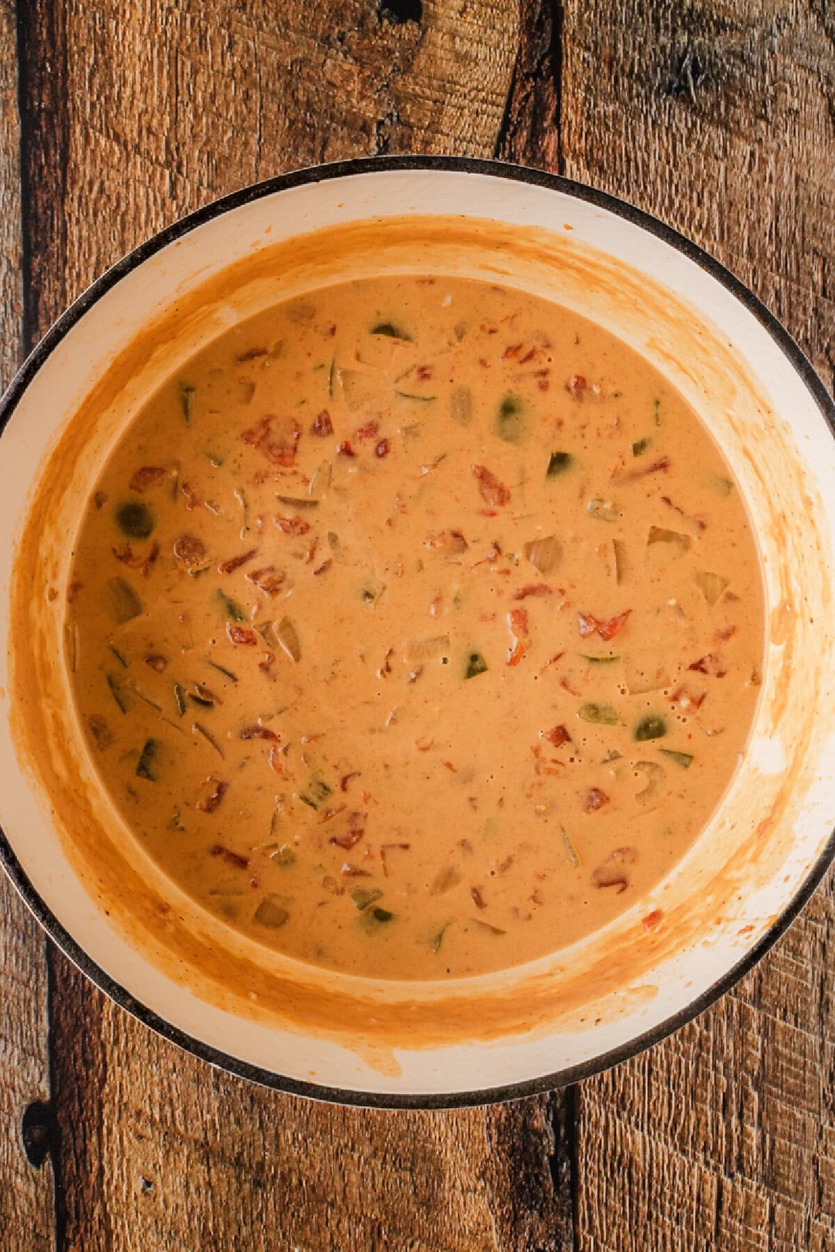 Chicken broth added to onion, peppers, garlic, and seasonings in a Dutch oven.