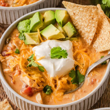 A small soup bowl filled with creamy chicken fajita soup topped with sour cream, avocado, and cilantro.