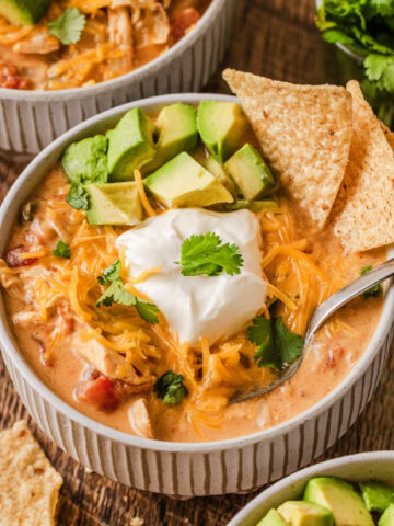 A small soup bowl filled with creamy chicken fajita soup topped with sour cream, avocado, and cilantro.