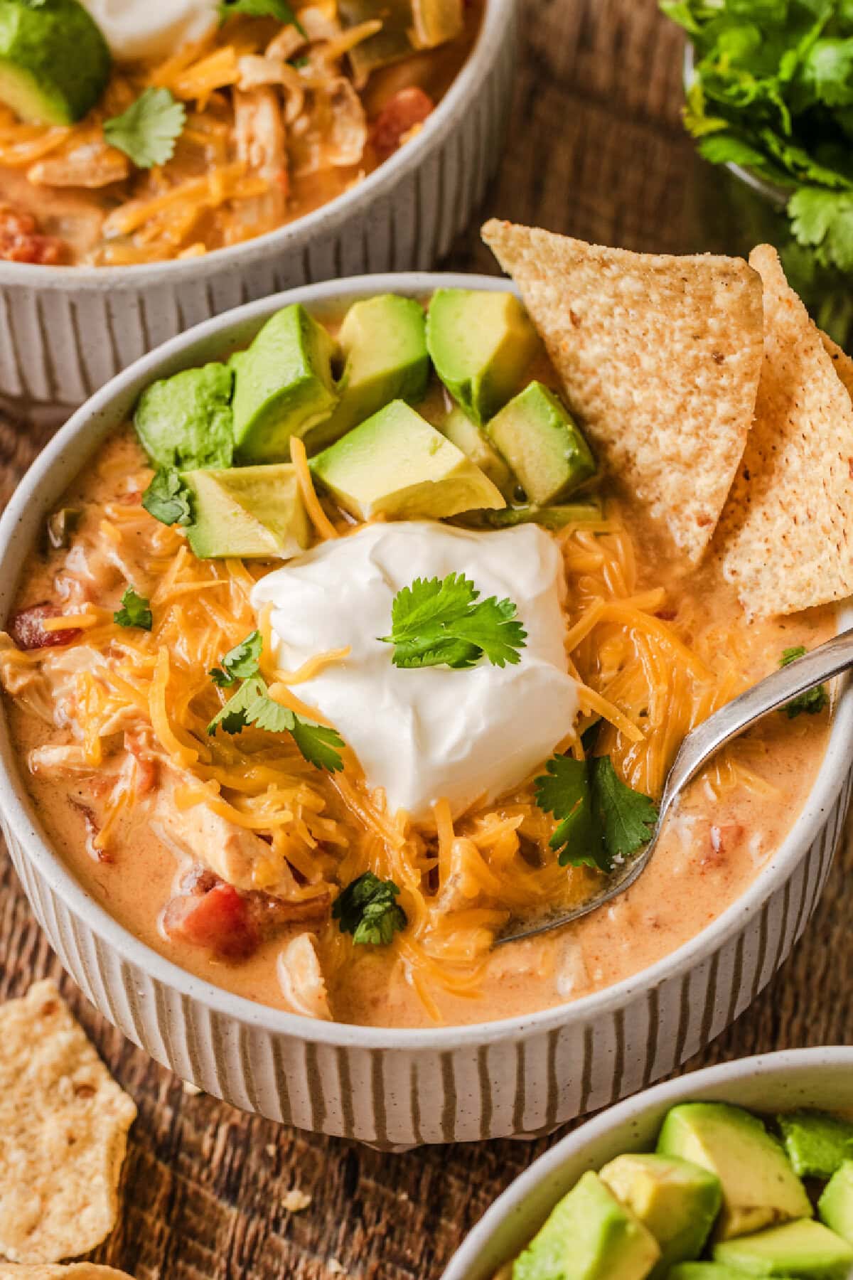 A small soup bowl filled with creamy chicken fajita soup topped with sour cream, avocado, and cilantro.