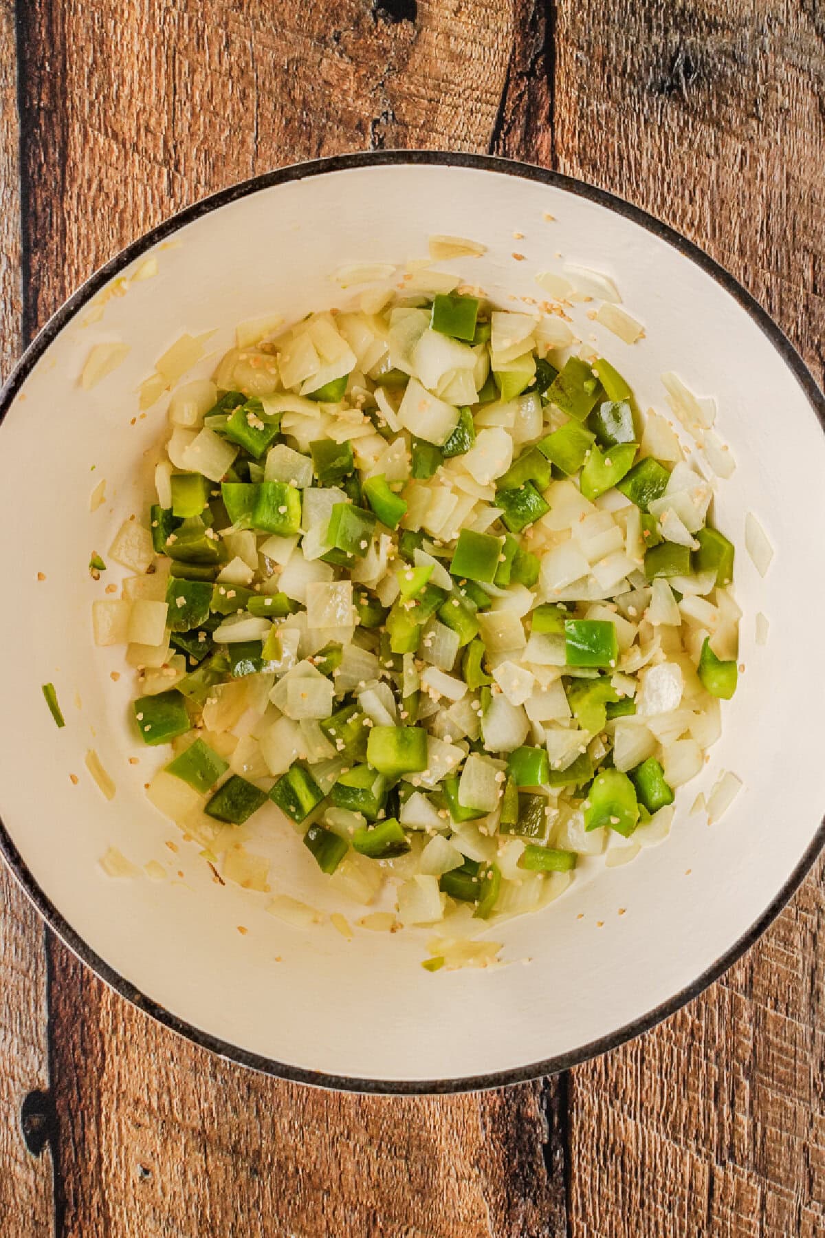 Green peppers, onions, and garlic added to a Dutch oven to simmer until tender.