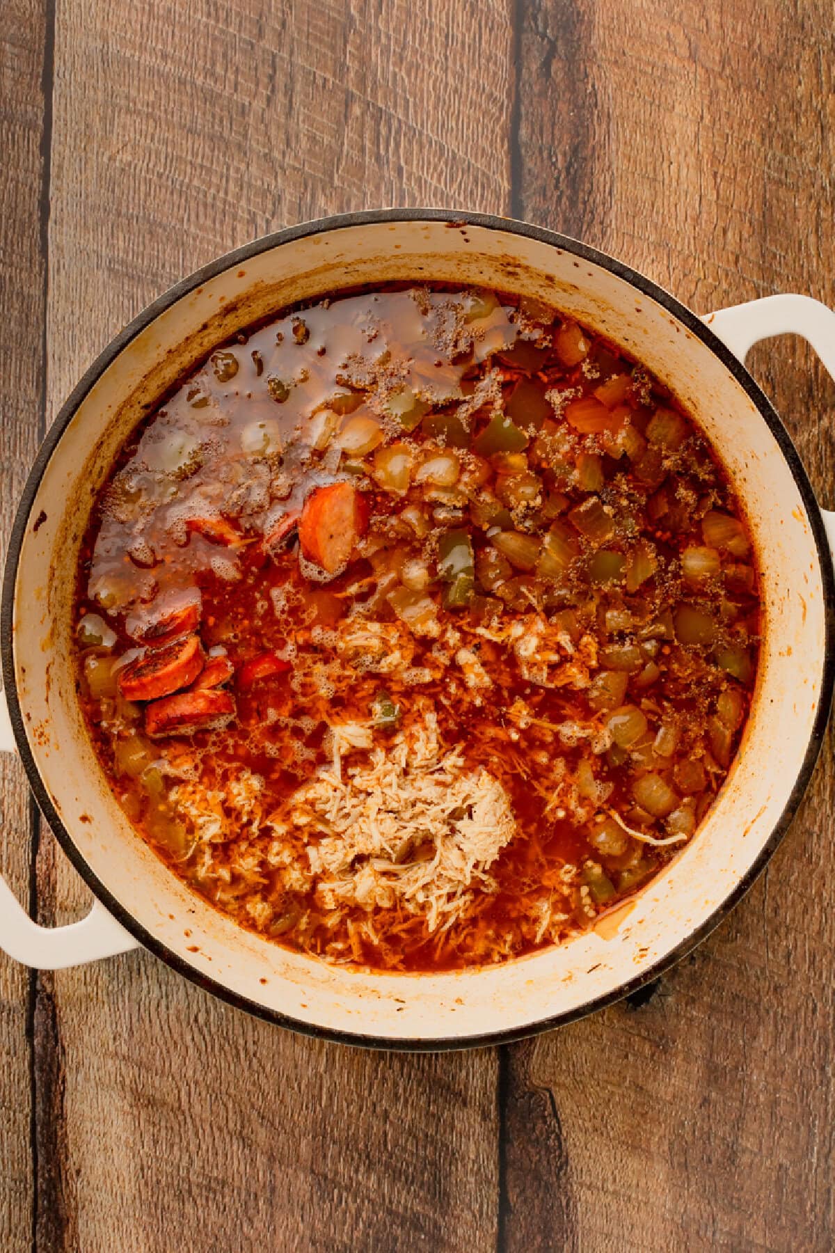 Shredded chicken added back into a Cajun mixture in a Dutch oven.