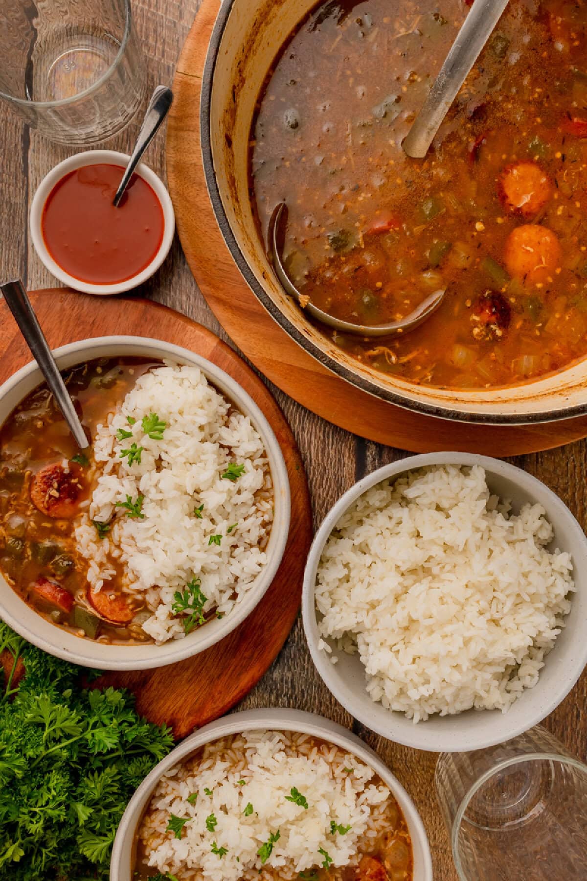 Chicken and sausage gumbo served over cooked rice in bowls.