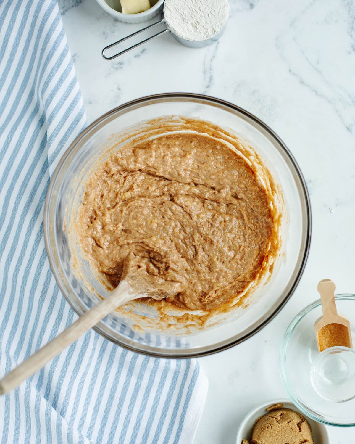 Eggs, banana, sugar, oil, yogurt, and dry ingredients combined in a glass mixing bowl.