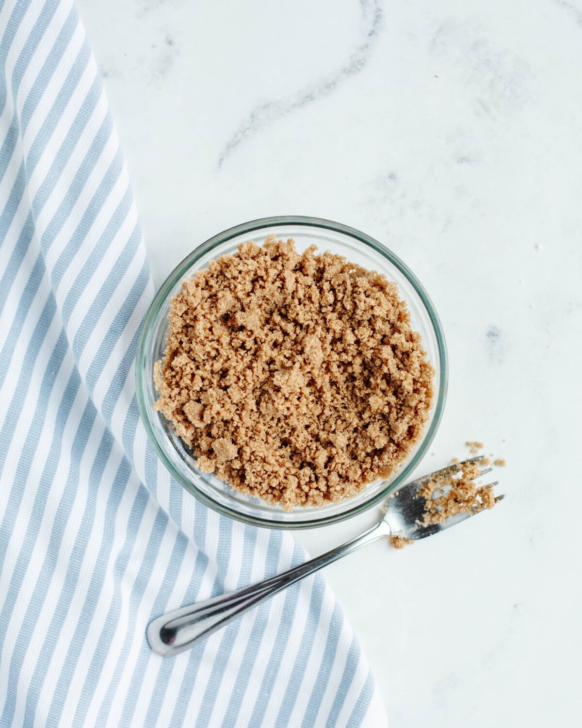 Flour, brown sugar, and cinnamon combined in a small glass bowl using a fork.
