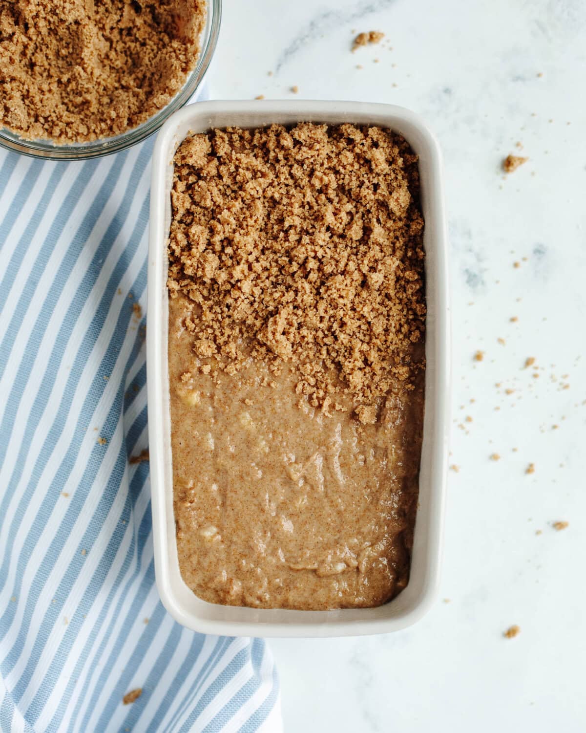 A crumble mixture sprinkled on top of quick bread batter in a loaf pan.