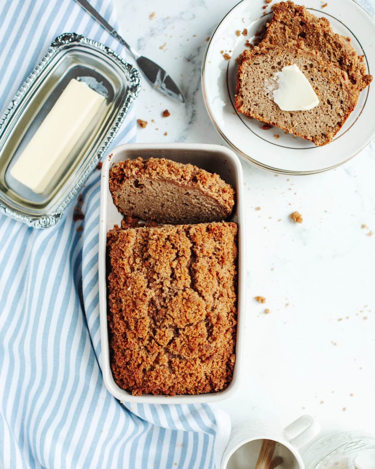 Baked loaf of cinnamon crumble banana bread in a white loaf pan.