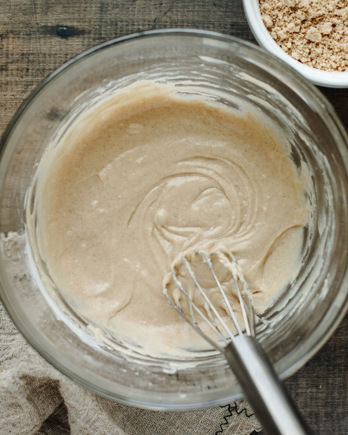 Coffee cake batter combined in a glass bowl using a whisk.