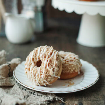 Two coffee cake donuts stacked on a white plate.