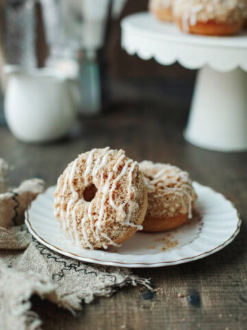 Two coffee cake donuts stacked on a white plate.