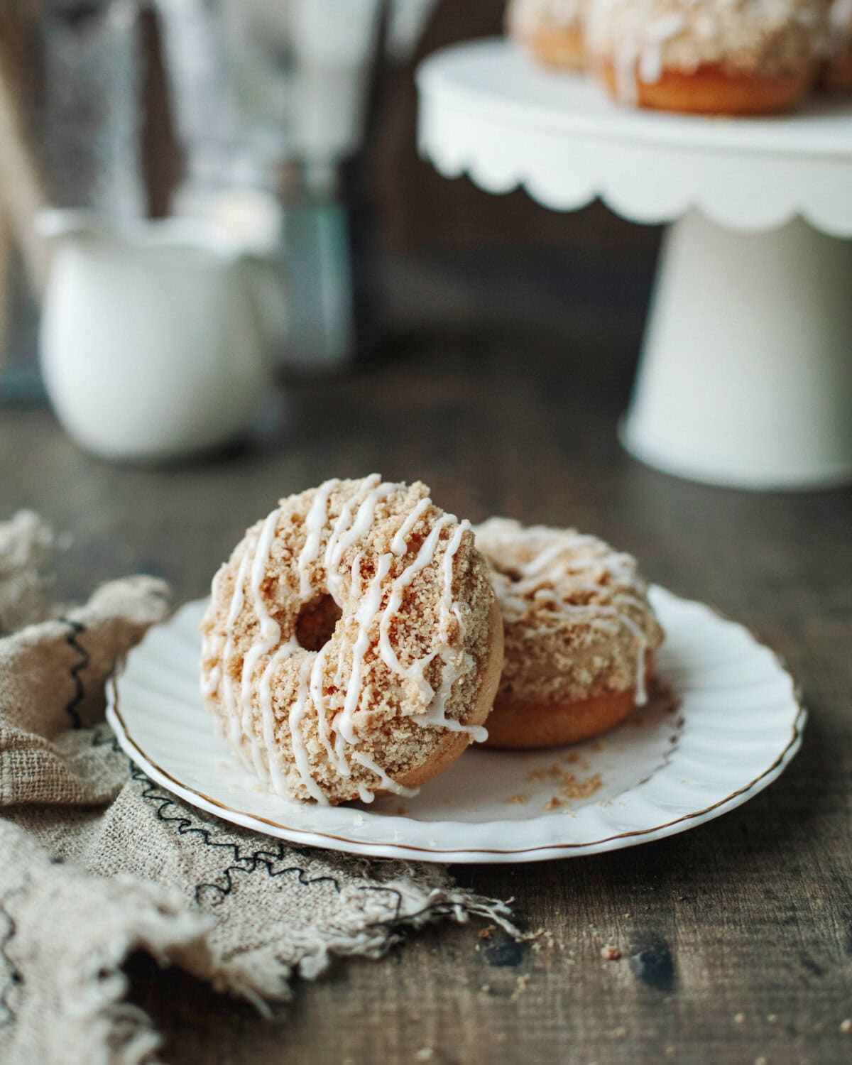 Two coffee cake donuts stacked on a white plate.
