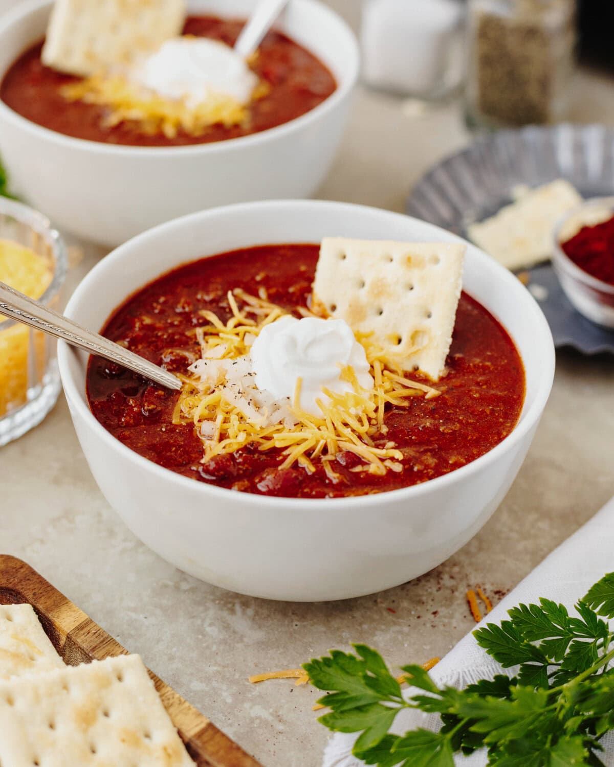 Beef chili topped with shredded cheddar cheese, sour cream, and saltine crackers.