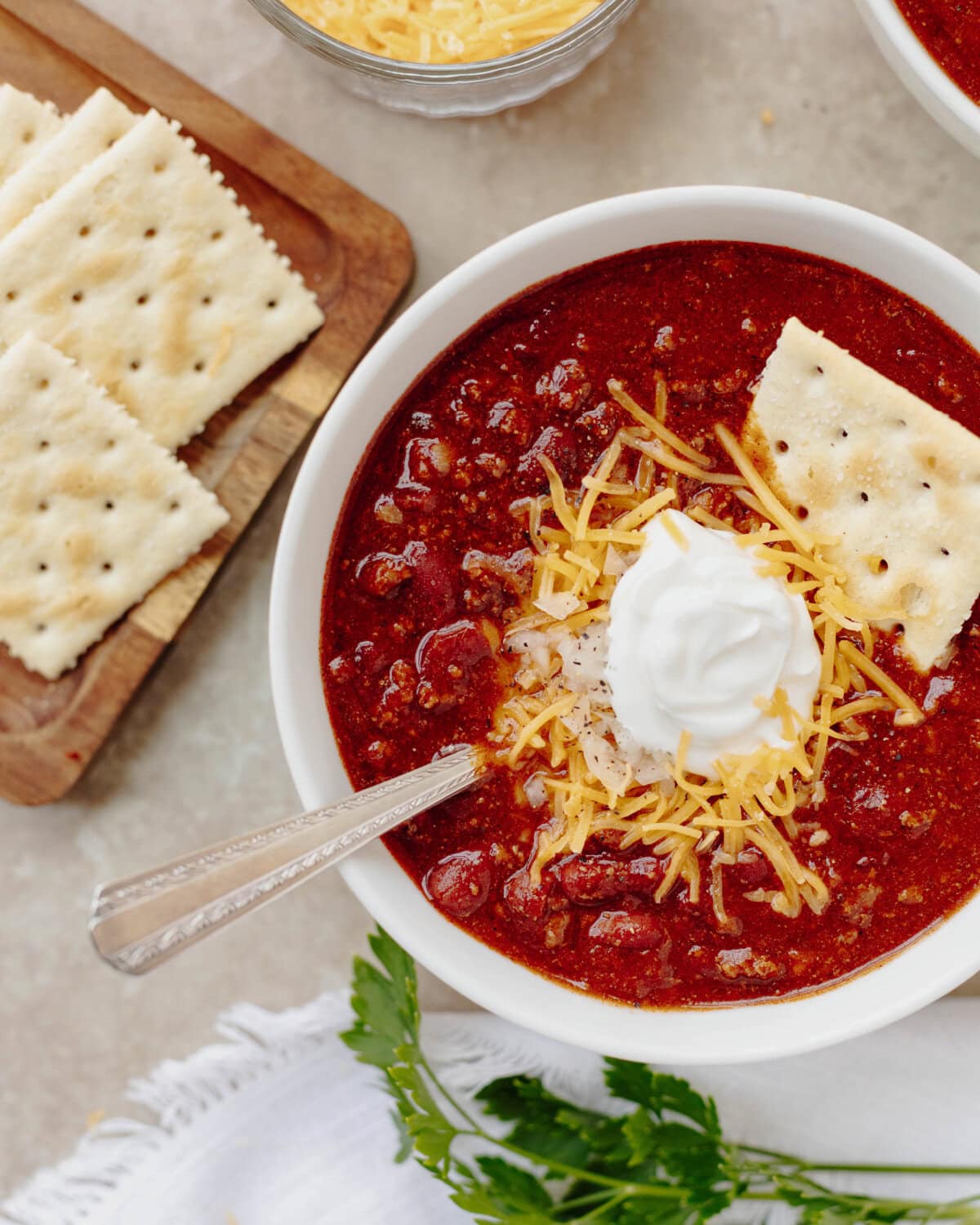 Game day chili with ground beef, beans, sour cream, shredded cheese, and crackers.