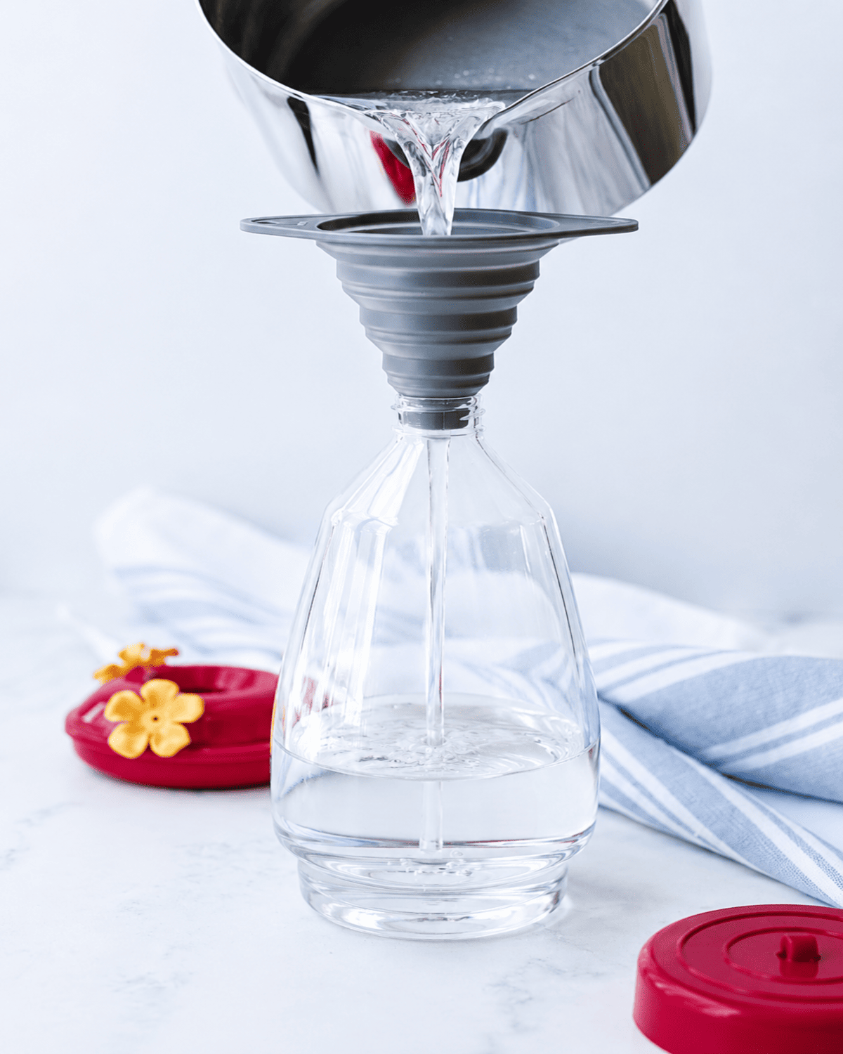 Sugar water poured through a funnel into a feeder.