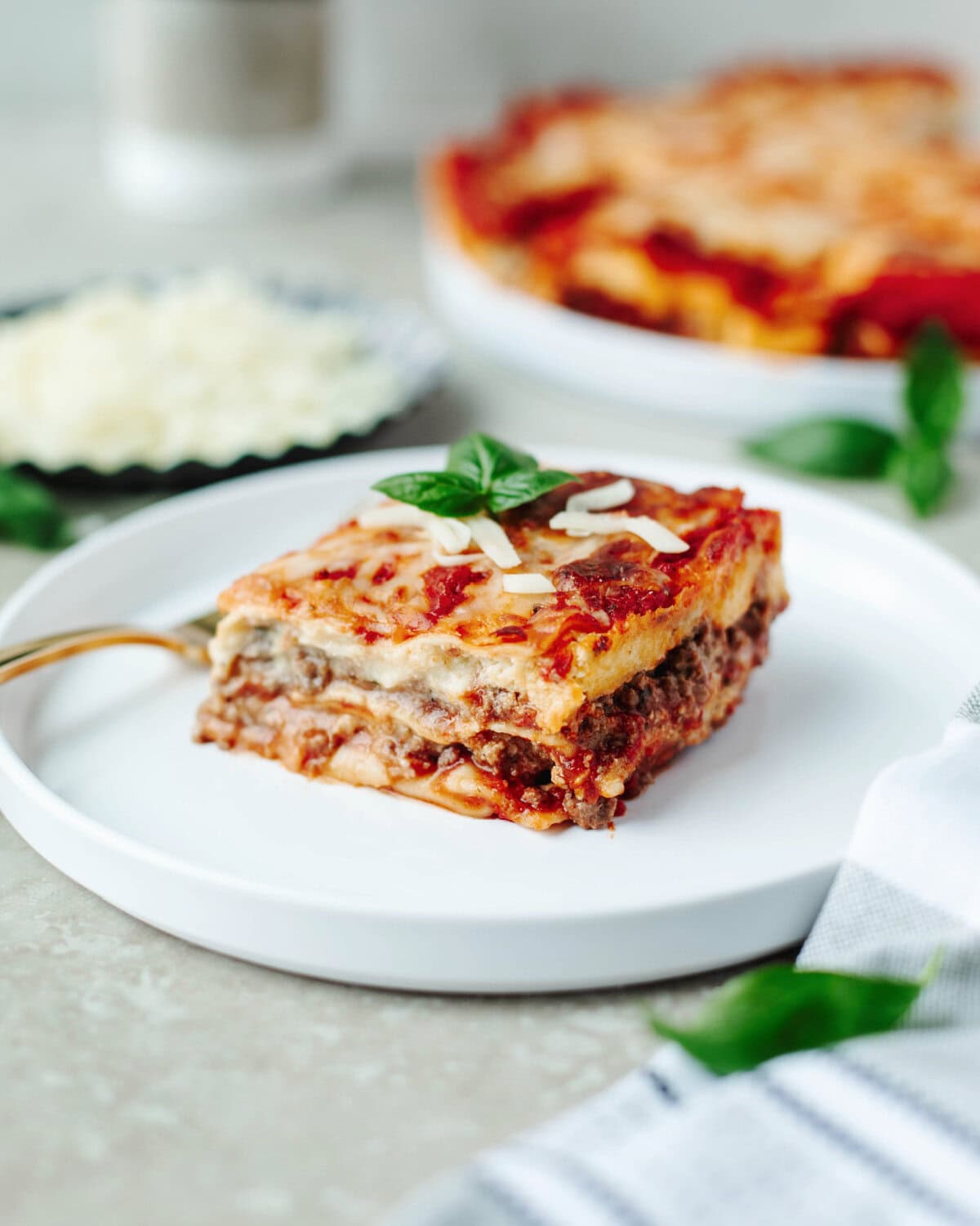 A slice of lasagna on a small white dinner plate ready to enjoy.