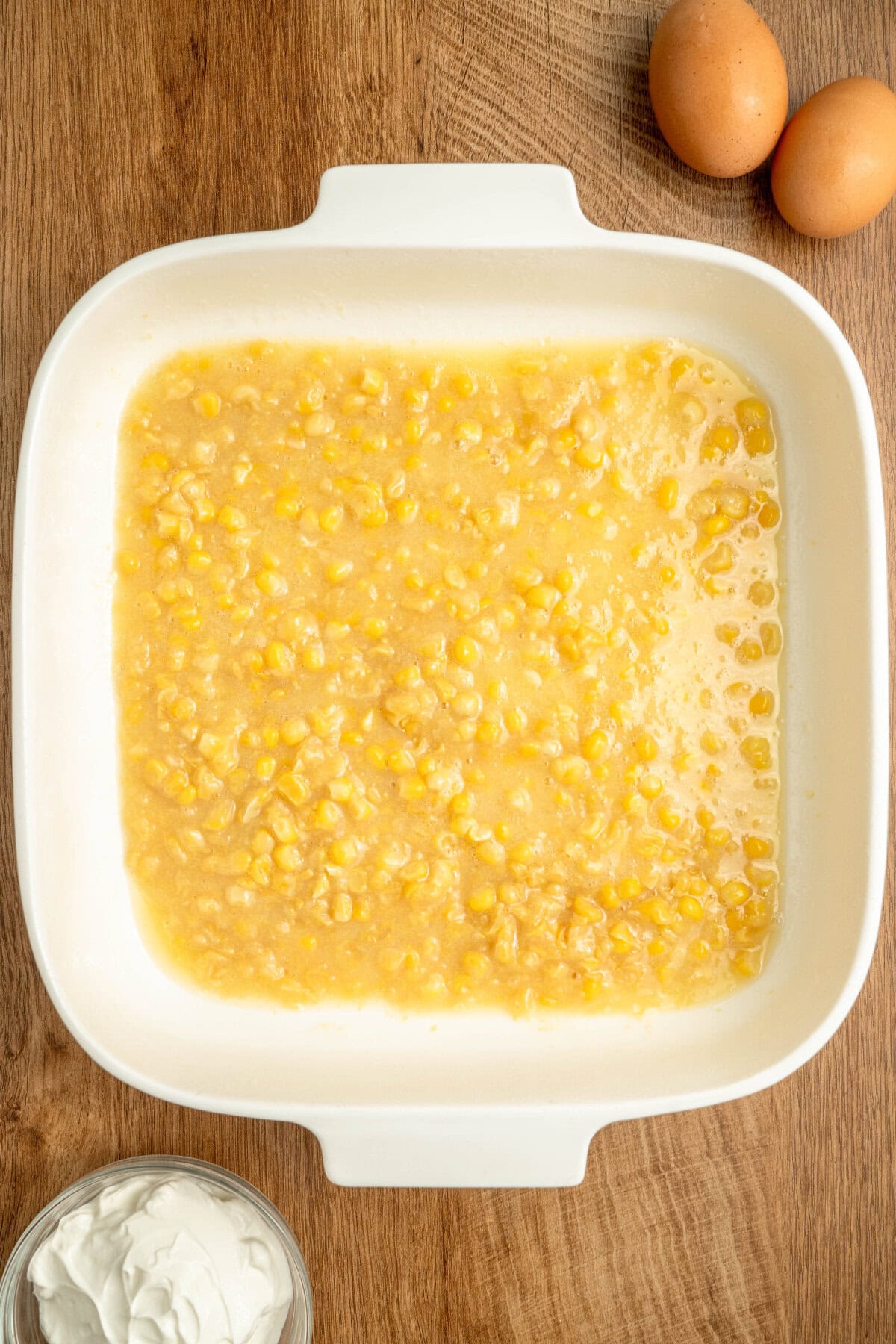 Corn and cream style corn added to the bottom of a white baking pan.