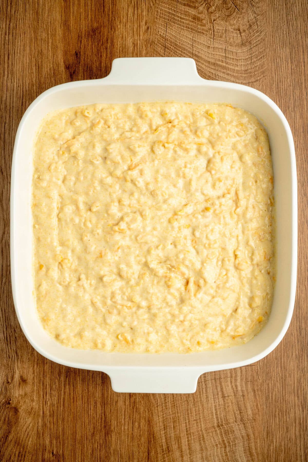 Batter spread evenly into a white prepared baking pan.
