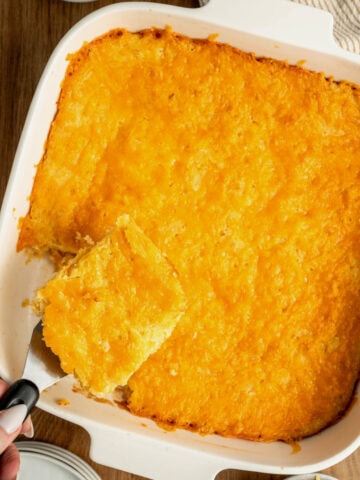 A baked jiffy cornbread casserole with a spatula removing a slice.