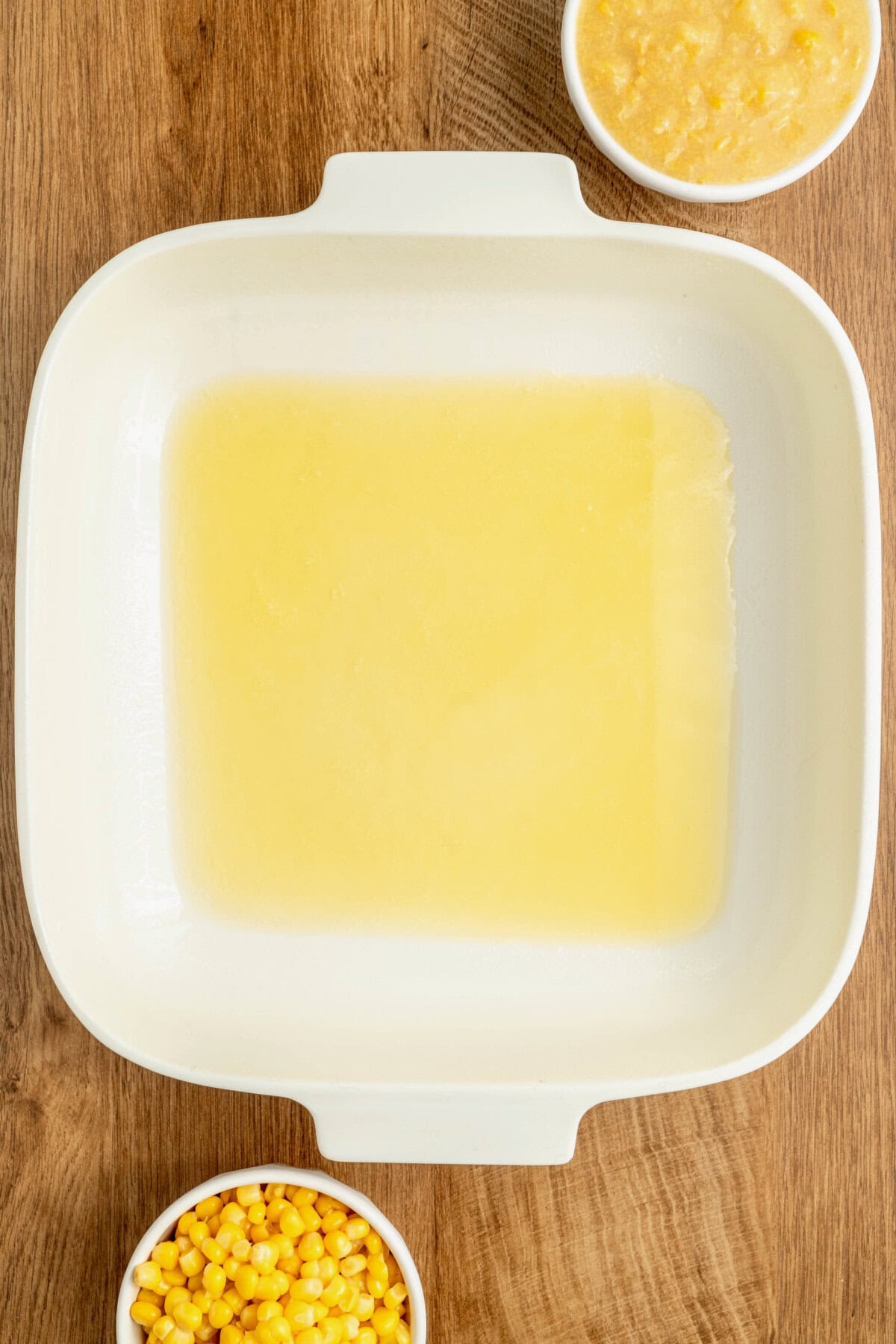 Melted butter coating the bottom of a white baking pan.