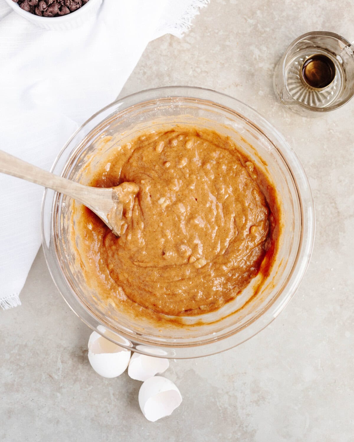 Oil, vanilla, pumpkin, and banana added to dry ingredients in a glass mixing bowl.